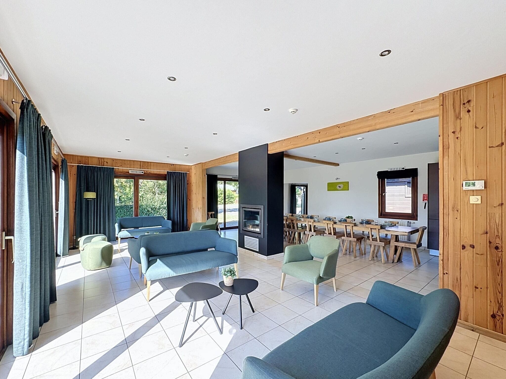 A spacious living area with a fireplace, multiple seating options, and a dining area with wooden tables and chairs.