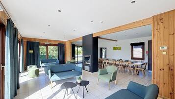 A spacious living area with a fireplace, multiple seating options, and a dining area with wooden tables and chairs.