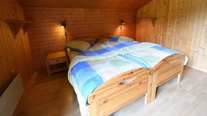 A wooden-paneled bedroom with a bed, bedside tables, and wall-mounted lamps.