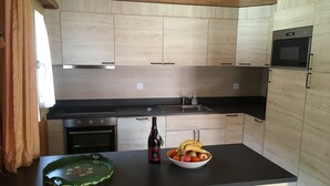 A modern kitchen with wooden cabinets, a black countertop, a built-in oven, and a microwave.