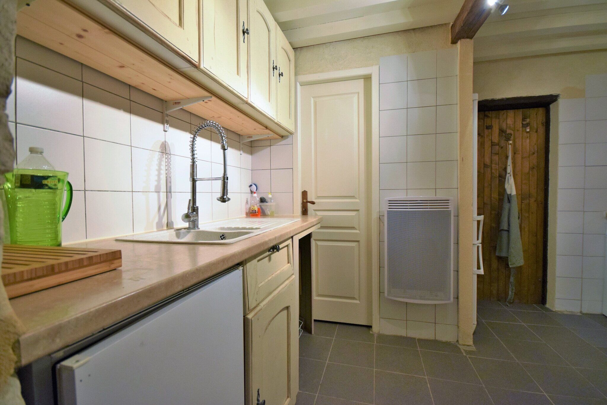 Una cocina compacta con un lavamanos, armarios de madera y un refrigerador pequeño.