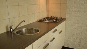 A kitchen with a stainless steel sink, a gas stove, and white cabinets. - Modern Apartment in Schin op Geul near Valkenburg (Schin op Geul)