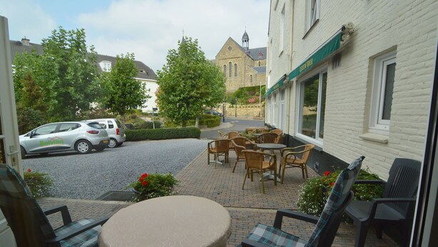 A courtyard with outdoor seating, a parked car, and a building with a sign. - Modern Apartment in Schin op Geul near Valkenburg (Schin op Geul)