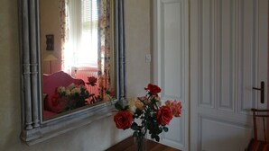 A room with a large mirror, a vase with flowers, and a door.