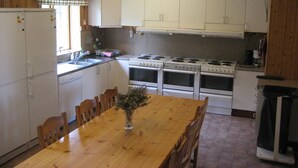 Una cocina con armarios de madera, una estufa y una mesa de comedor con sillas.