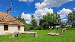 Una casa rústica con techo de tejas, un columpio y una zona de estar cubierta.