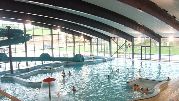 Una piscina interior con múltiples carriles y un tobogán de agua.