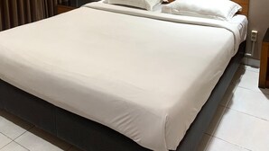 Una habitación de hotel con una cama grande, cabecera de madera, dos mesitas de noche y una lámpara de pared.