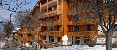 Een meerlaags houten gebouw met balkons, omringd door sneeuw.