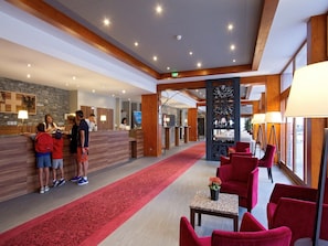 Eine Hotelhalle mit einer Rezeption, einem roten Teppich und roten Stühlen.