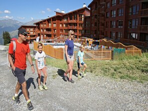 A family walking on a gravel path with a lodge in the background. - Modern Mountain Base (Bourg-Saint Maurice)