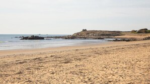 A beach with a rocky outcrop and a building on the right. - Cozy Brittany Escape (Erdeven)