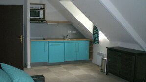 A compact kitchen with teal cabinets, a microwave, and a sink. - Cozy Brittany Escape (Erdeven)