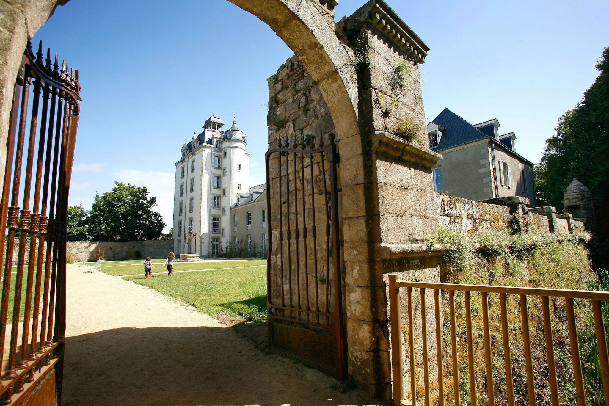 Un bâtiment historique doté d’une grande entrée en arc de cercle, d’un chemin menant à une cour intérieure et d’une haute tour.