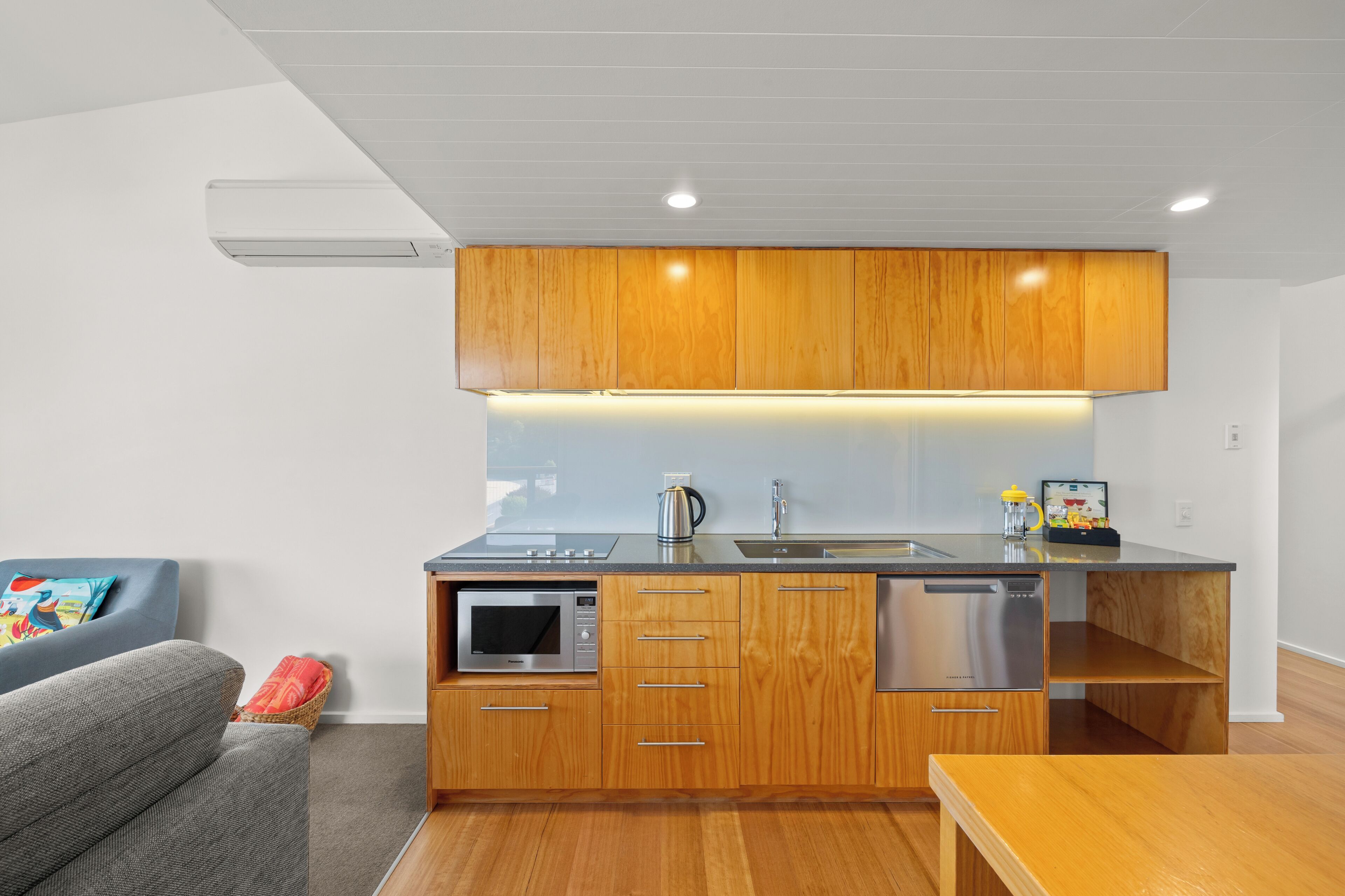 A modern kitchen with wooden cabinets, a built-in microwave, and a dishwasher.