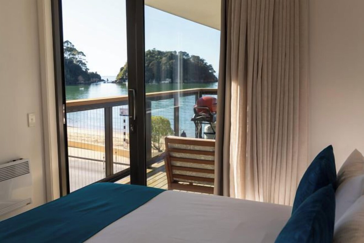 Habitación de hotel con cama, vista a un cuerpo de agua y balcón con una silla.