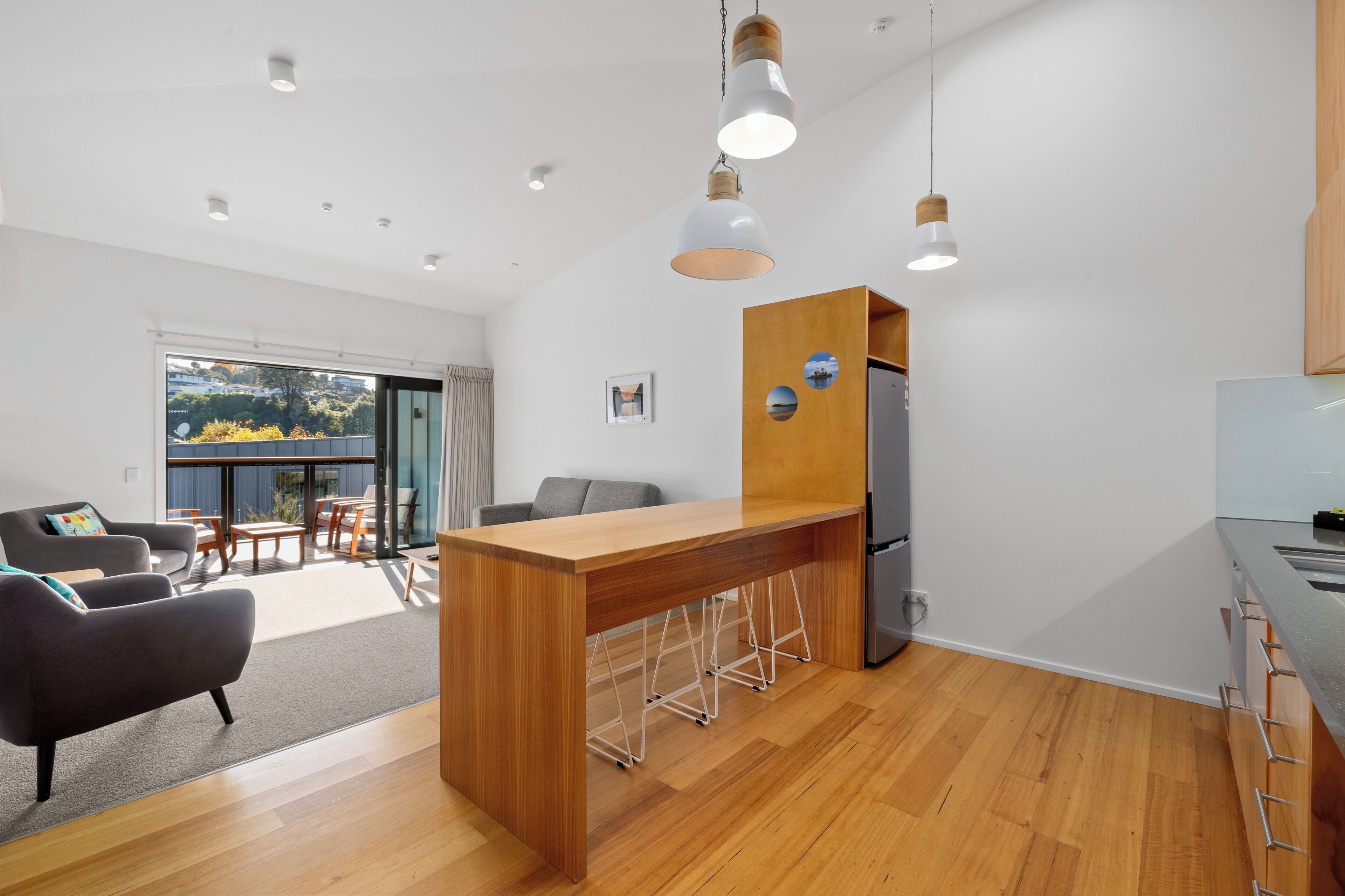 A modern kitchen with a wooden island, bar stools, and a refrigerator.