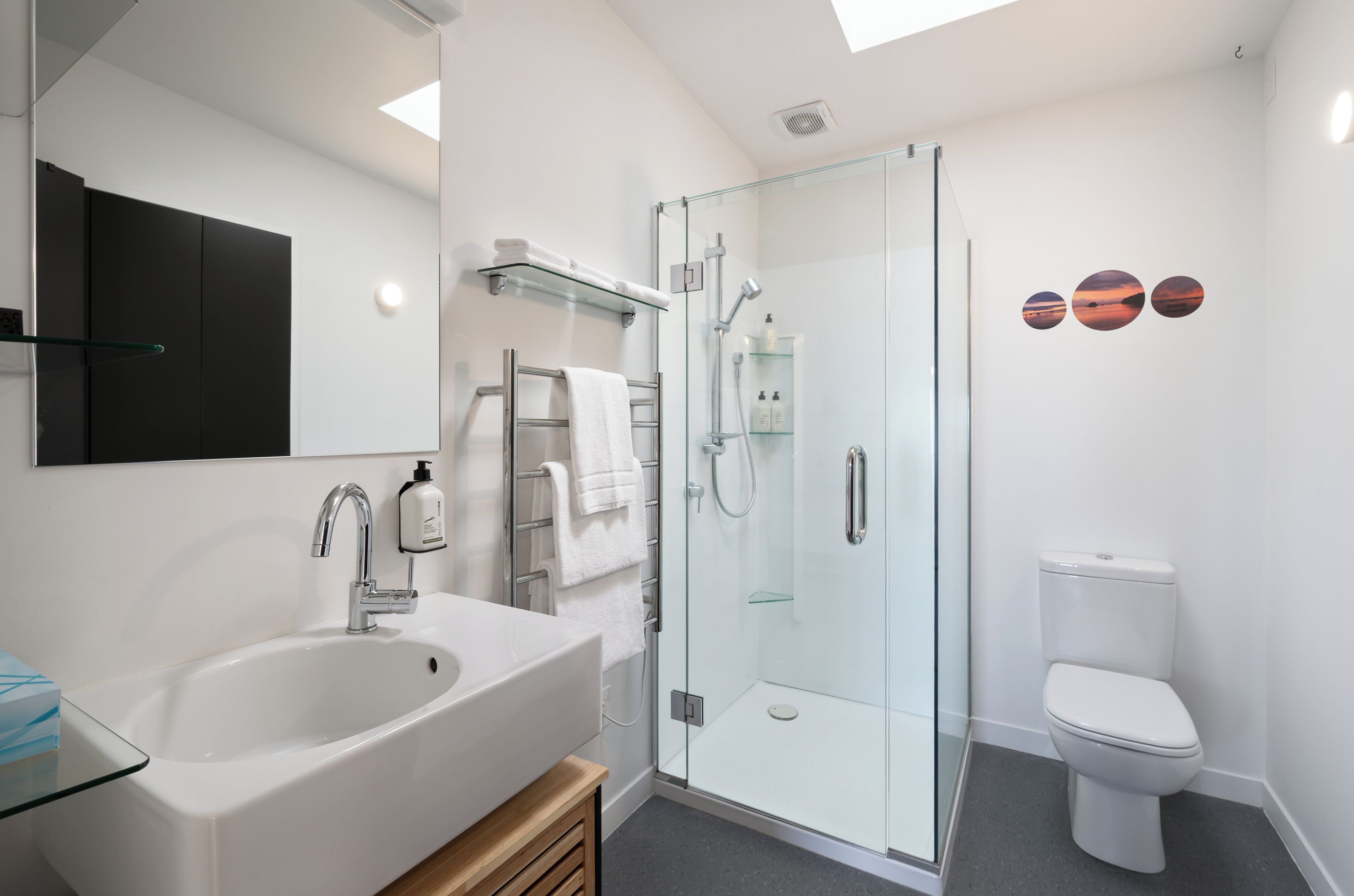 A modern bathroom with a glass-enclosed shower, a white sink, and a toilet.