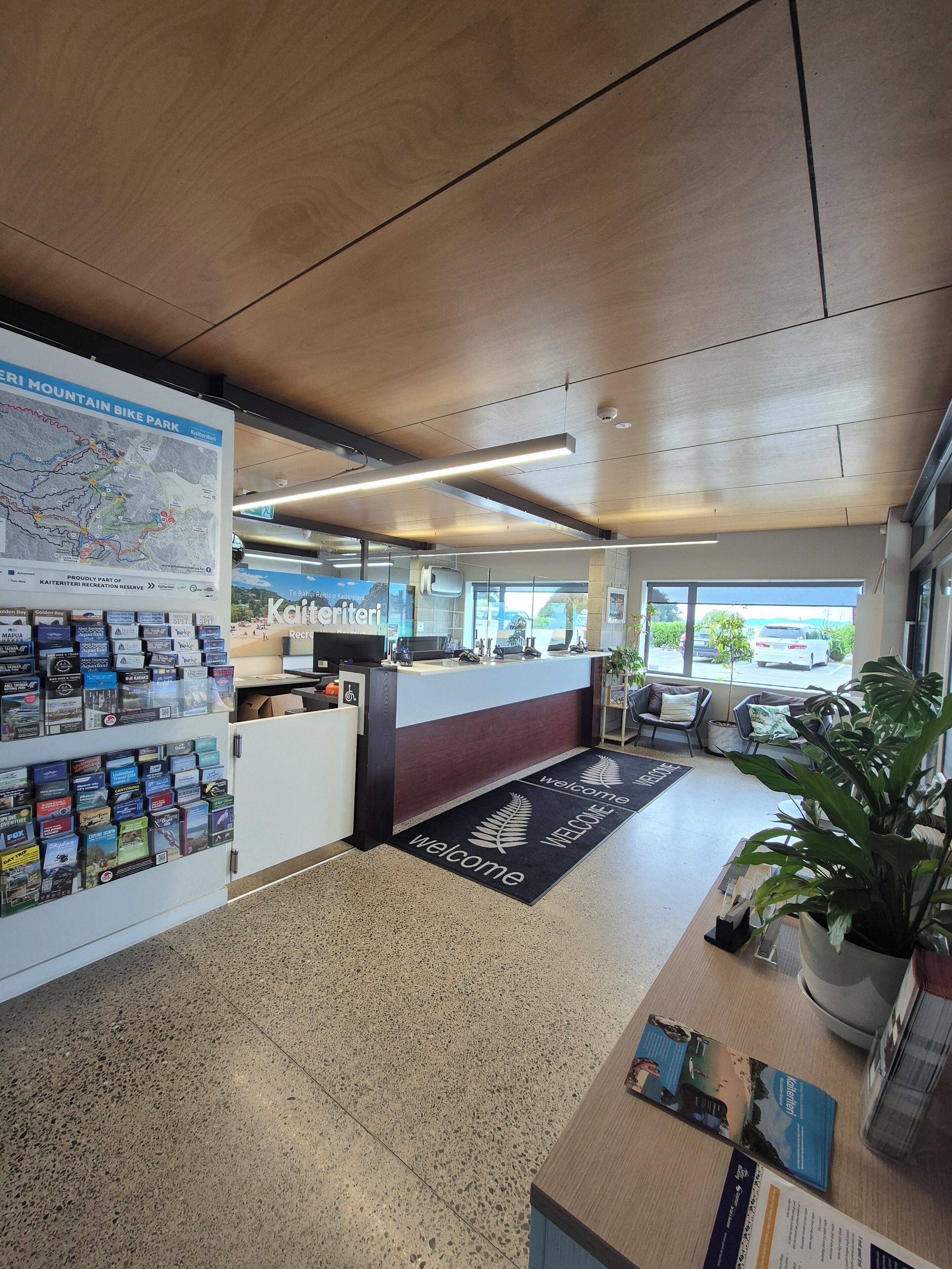 A reception area with a map, informational brochures, a reception desk, seating area, and a view of the outside.