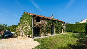 A stone house with a red-tiled roof, ivy-covered walls, and a gravel driveway. - Poolside Haven in Salles (Salles-De-Belvès)
