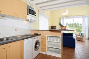Une cuisine compacte équipée d’un lave-linge, d’un four à micro-ondes et d’un coin repas avec vue.