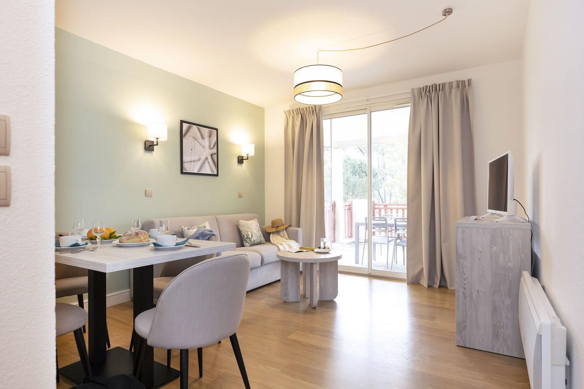 Una sala de estar moderna con comedor, un sofá, una mesa de centro y un televisor sobre un mueble.