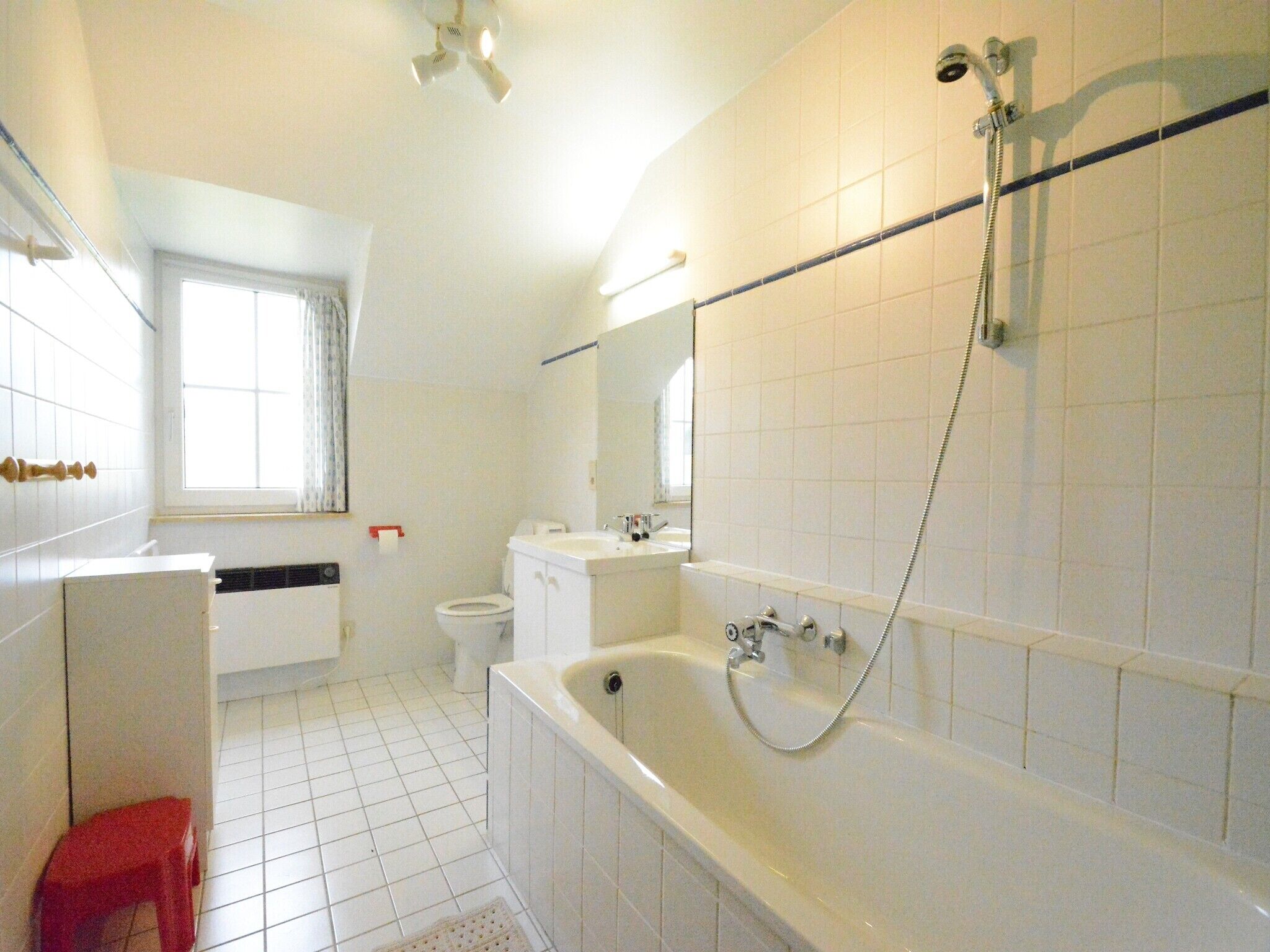A bathroom with a bathtub, toilet, sink, and a window.
