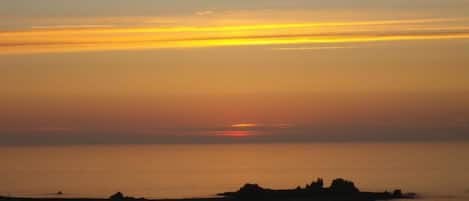 A sunset over a calm sea with boats anchored near the shore.