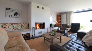 Un salon moderne avec une cheminée, un canapé, une table basse et un téléviseur.