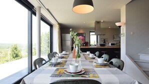 Une table à manger dressée avec des tasses et des soucoupes blanches, un vase rempli de fleurs et une nappe à carreaux.