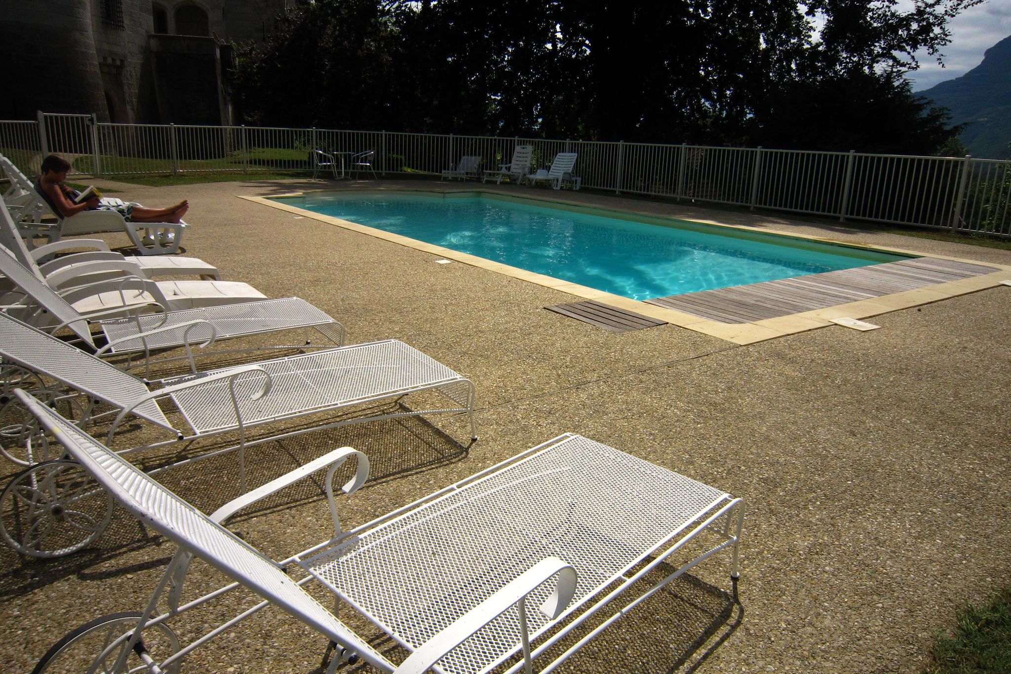A pool area with lounge chairs and a metal table.