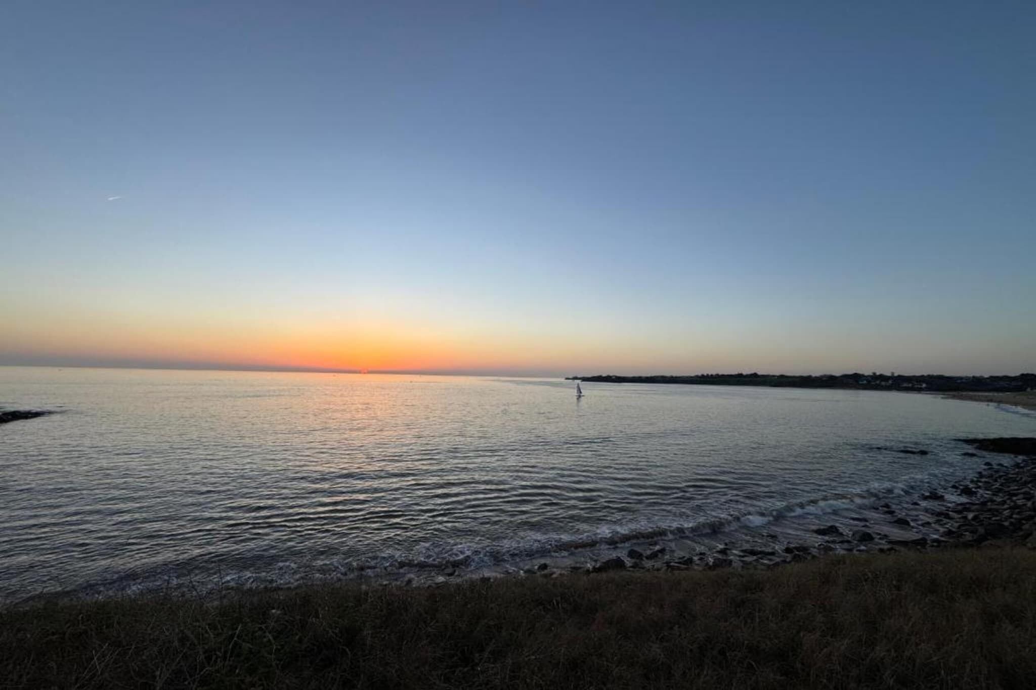 Acqua calma al tramonto, con una costa in lontananza.