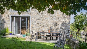 A stone building with a patio area featuring a table and chairs, surrounded by greenery and a stone wall. - Tranquil Stay in Ardennes (Gimnée)