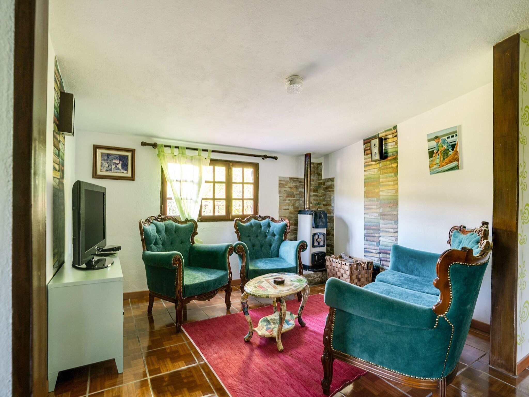 A living room with a fireplace, green upholstered chairs, a television, and a red rug.