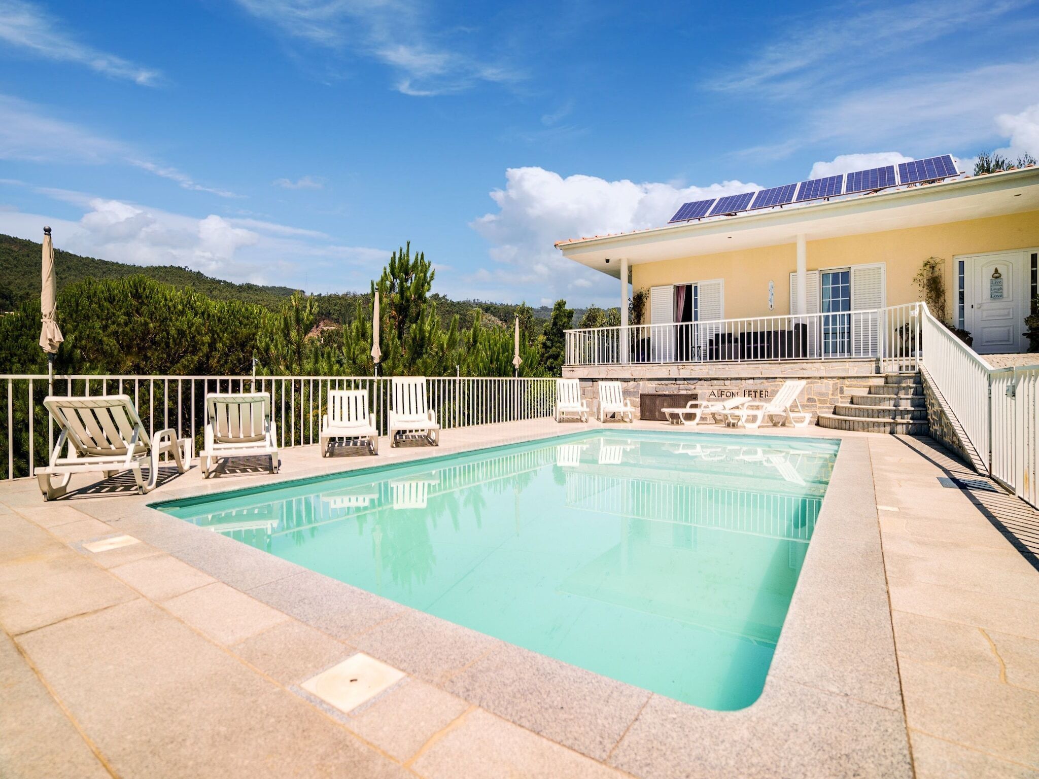 A swimming pool with lounge chairs and a building with solar panels.