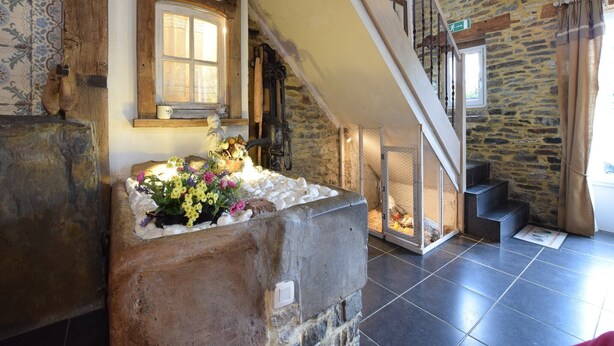 Un intérieur rustique avec une cheminée en pierre, un banc en bois et un escalier menant à un niveau supérieur.