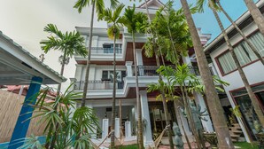 A multi-story building with a balcony, palm trees, and a hammock. - Travellerhome Angkor (Siem Reap)