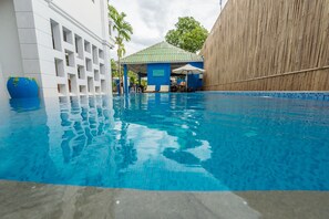 A swimming pool with a tiled edge, a covered seating area, and a bamboo wall. - Travellerhome Angkor (Siem Reap)