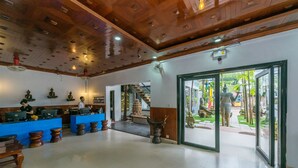 A spacious lobby with a wooden ceiling, a reception desk, and a staircase leading to an outdoor area with plants. - Travellerhome Angkor (Siem Reap)