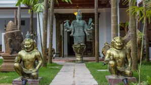 A pathway leading to a temple with statues and a Buddha figure. - Travellerhome Angkor (Siem Reap)