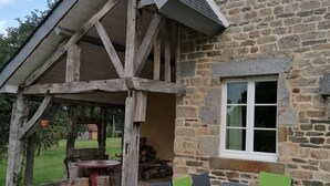 Ein Steinhaus mit einer Holzveranda und einem Tisch mit Stühlen.
