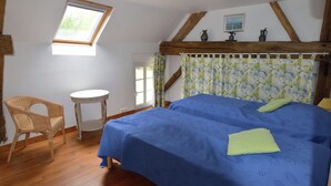 Ein Zimmer mit einem Bett, einem Sessel, einem kleinen Tisch und einem Fenster.