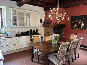 A dining area with a wooden table and chairs, a fireplace, and a chandelier. - Luxurious holiday home with private pool (Buzon)