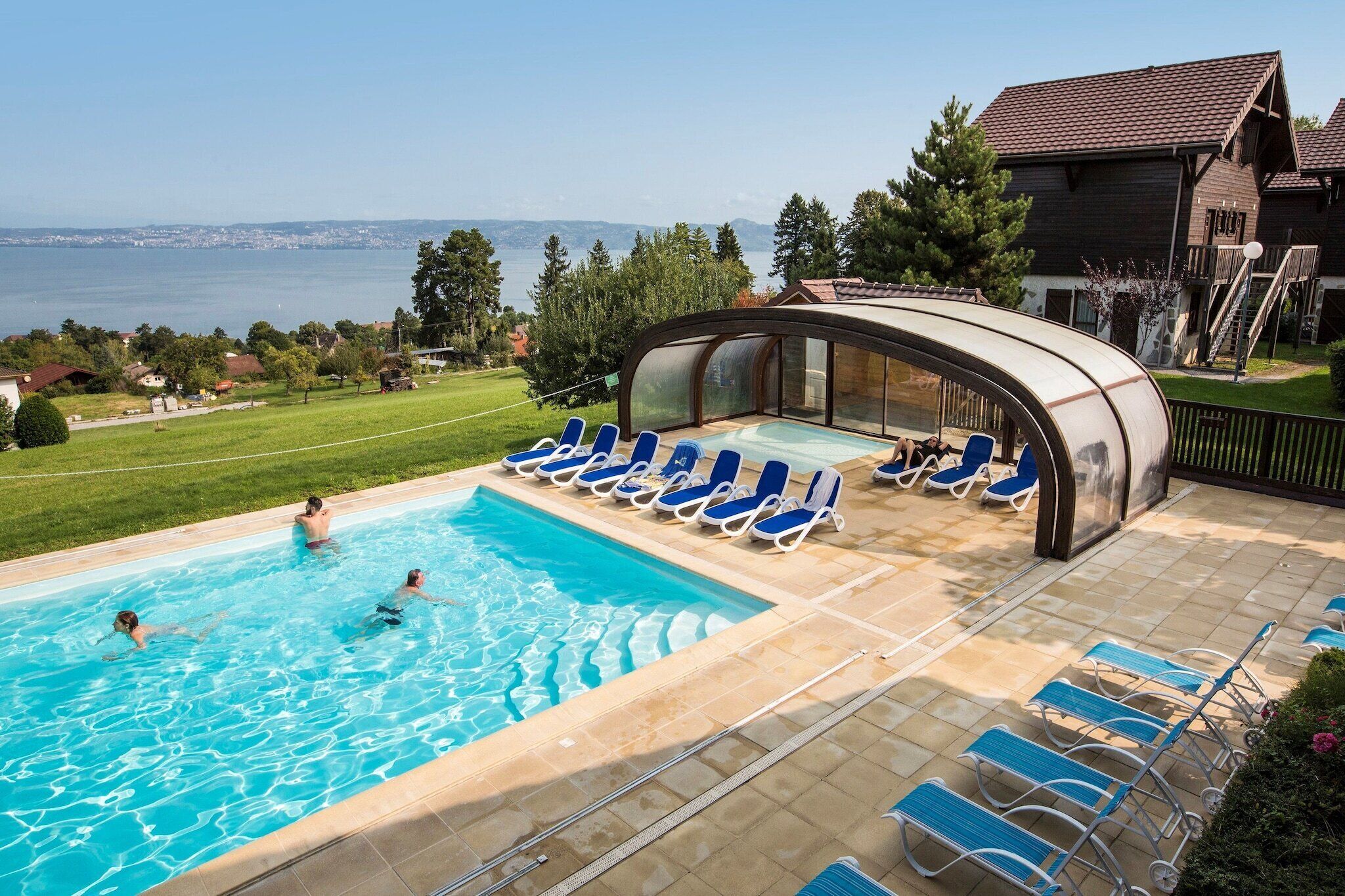 A swimming pool with lounge chairs and a covered area, overlooking a body of water.