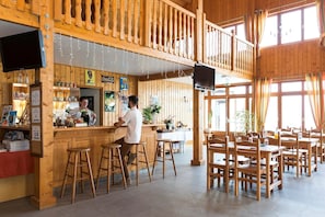A wooden interior with a bar area, seating, and a television. - Apartment near Lake Geneva (Bernex)