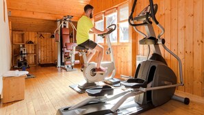Una persona utilizza un tapis roulant ellittico in una stanza con pareti e pavimento in legno.
