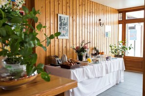 A breakfast buffet setup with a wooden wall, a framed photo, and various food items. - Apartment near Lake Geneva (Bernex)