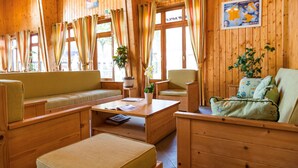 Un accogliente interno di una baita in legno con un divano, poltrone, un tavolino da caffè e un tavolo da pranzo.