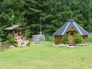 A rustic cabin with a wooden door and a chimney, surrounded by a grassy area and dense forest. - Forest Retreat in Jägersgrün (Jägersgrün)