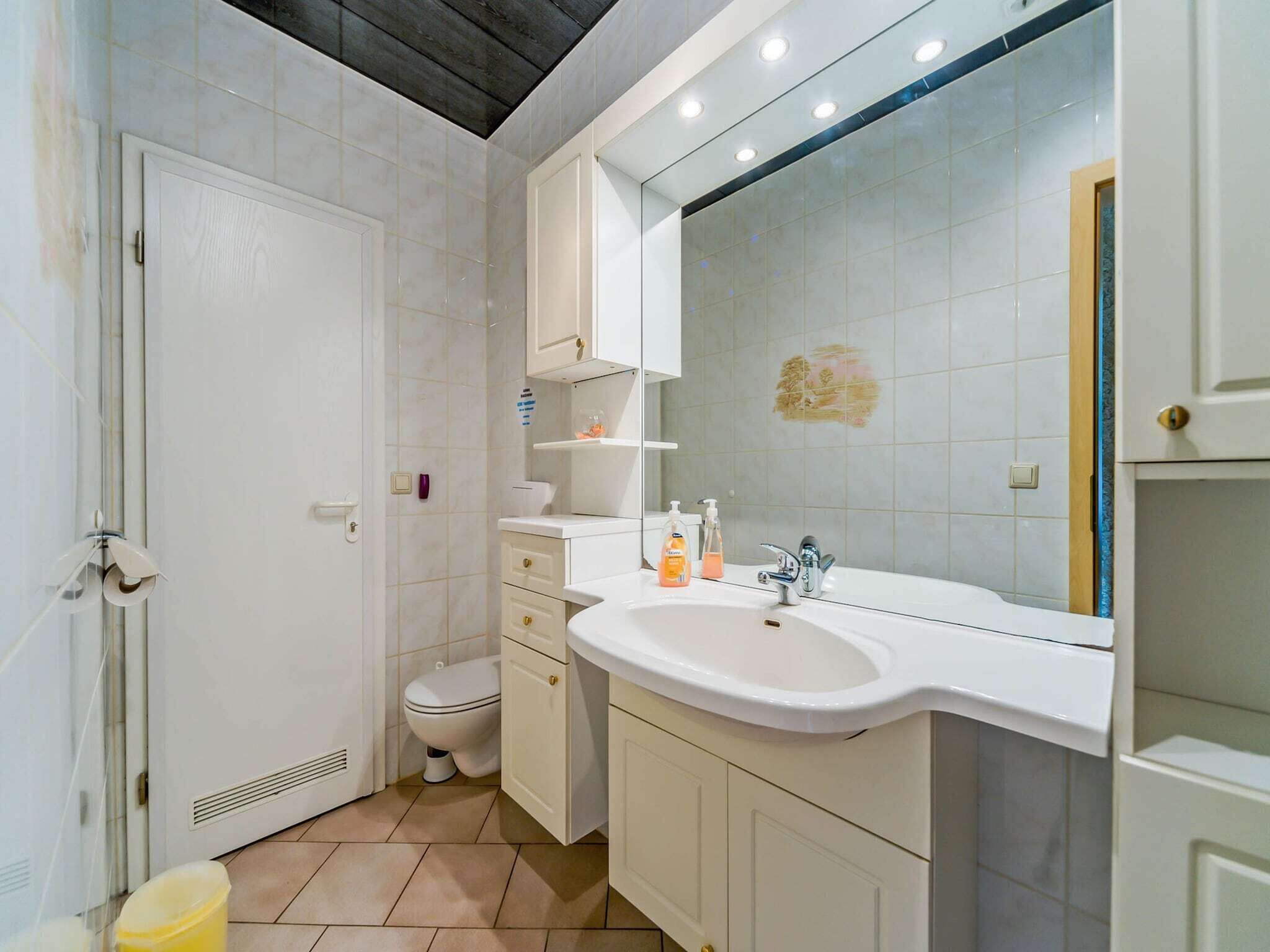 Ein Badezimmer mit weißem Waschbecken, Spiegel und Toilette.